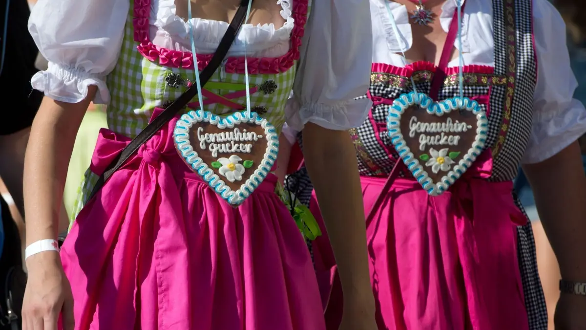 ARCHIV - Besucherinnen in Trachten gehen am 26.09.2014 in Stuttgart (Baden-Württemberg) über das Cannstatter Volksfest und tragen Lebkuchenherzen. Foto: Sebastian Kahnert/dpa (zu dpa «Erstmals Dirndl-Leihservice auf dem Wasen» vom 02.09.2016) +++(c) dpa - Bildfunk+++