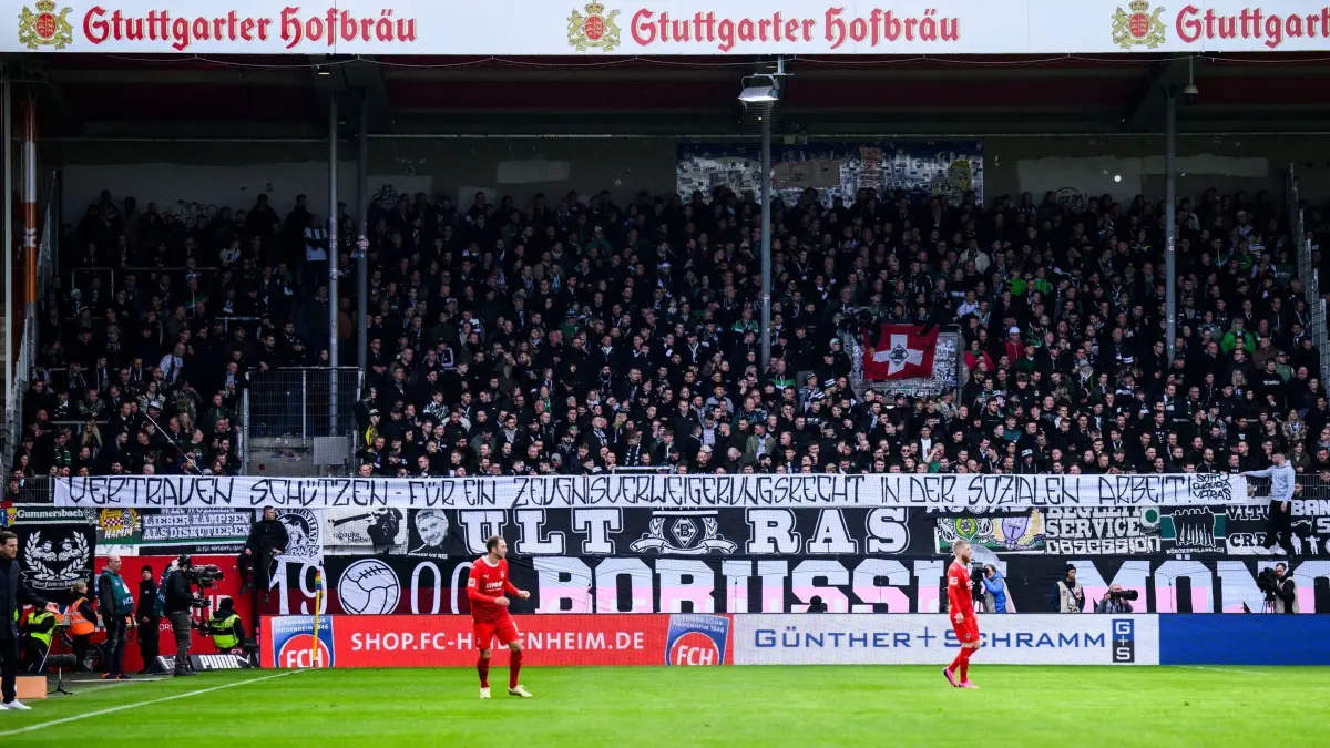 Fußball: Bundesliga, 1. FC Heidenheim — Borussia Mönchengladbach, 26. Spieltag, Voith–Arena. Fans aus Gladbach stehen während des Spiels im Fanblock und halten ein Transparent „Vertrauen schützen — für ein Zeugnisverweigerungsrecht in der sozialen Arbeit!“