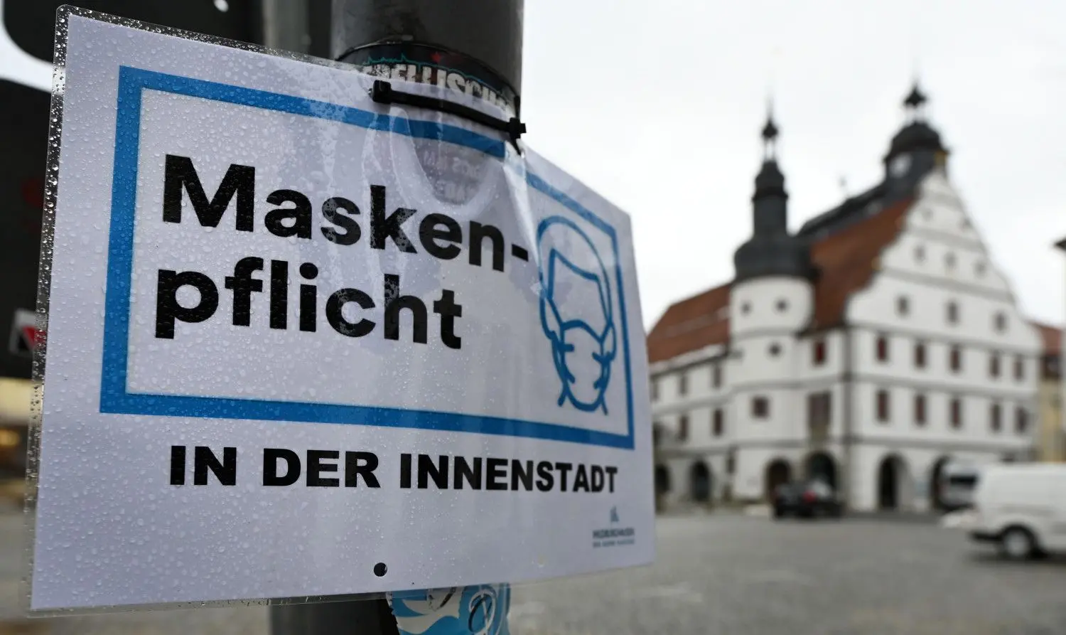 "Maskenpflicht in der Innenstadt" steht auf einem Schild neben dem Rathaus in Hildburghausen (Thüringen).