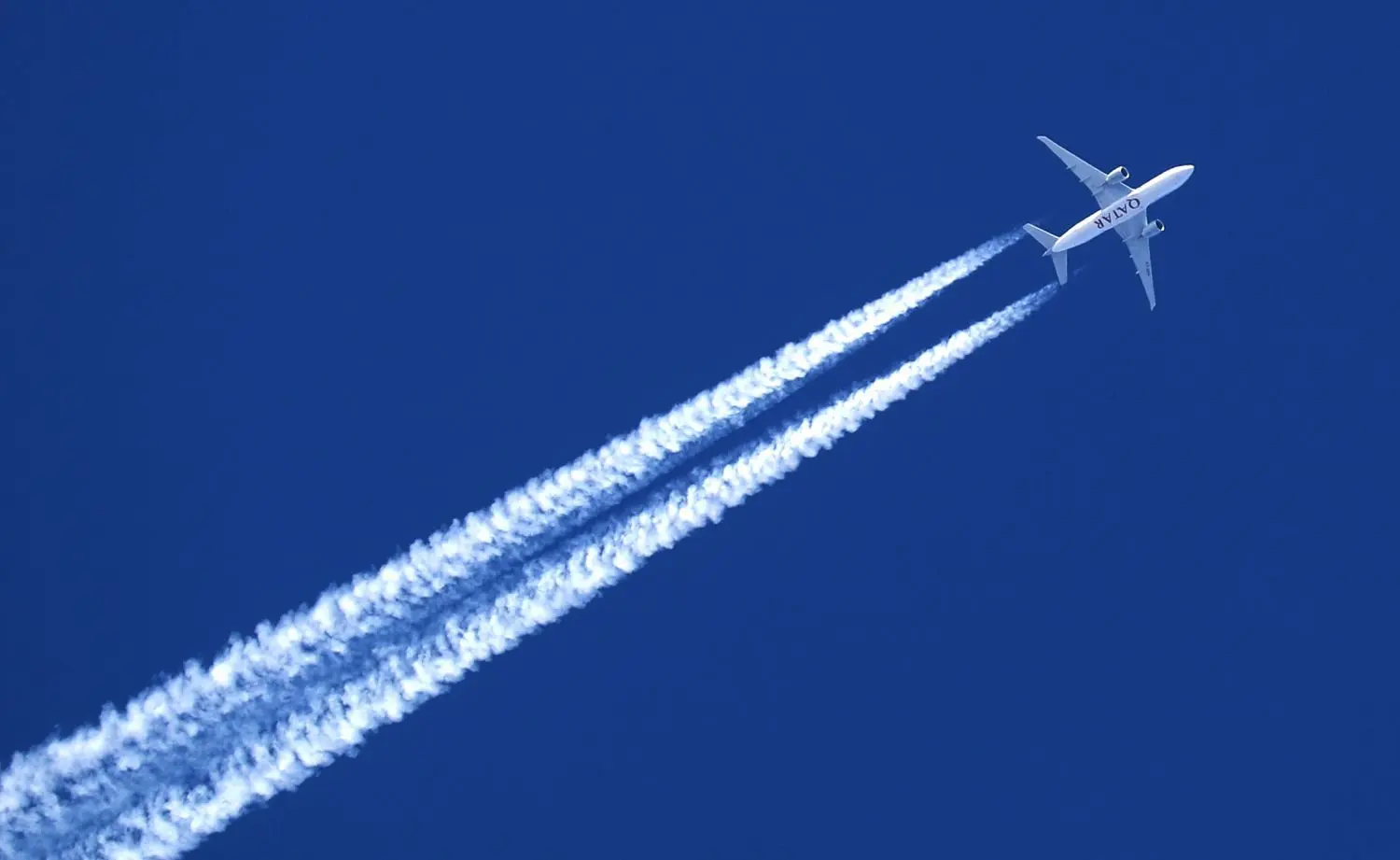 Ein Flugzeug hinterlässt Kondensstreifen am wolkenlosem Himmel.⇥