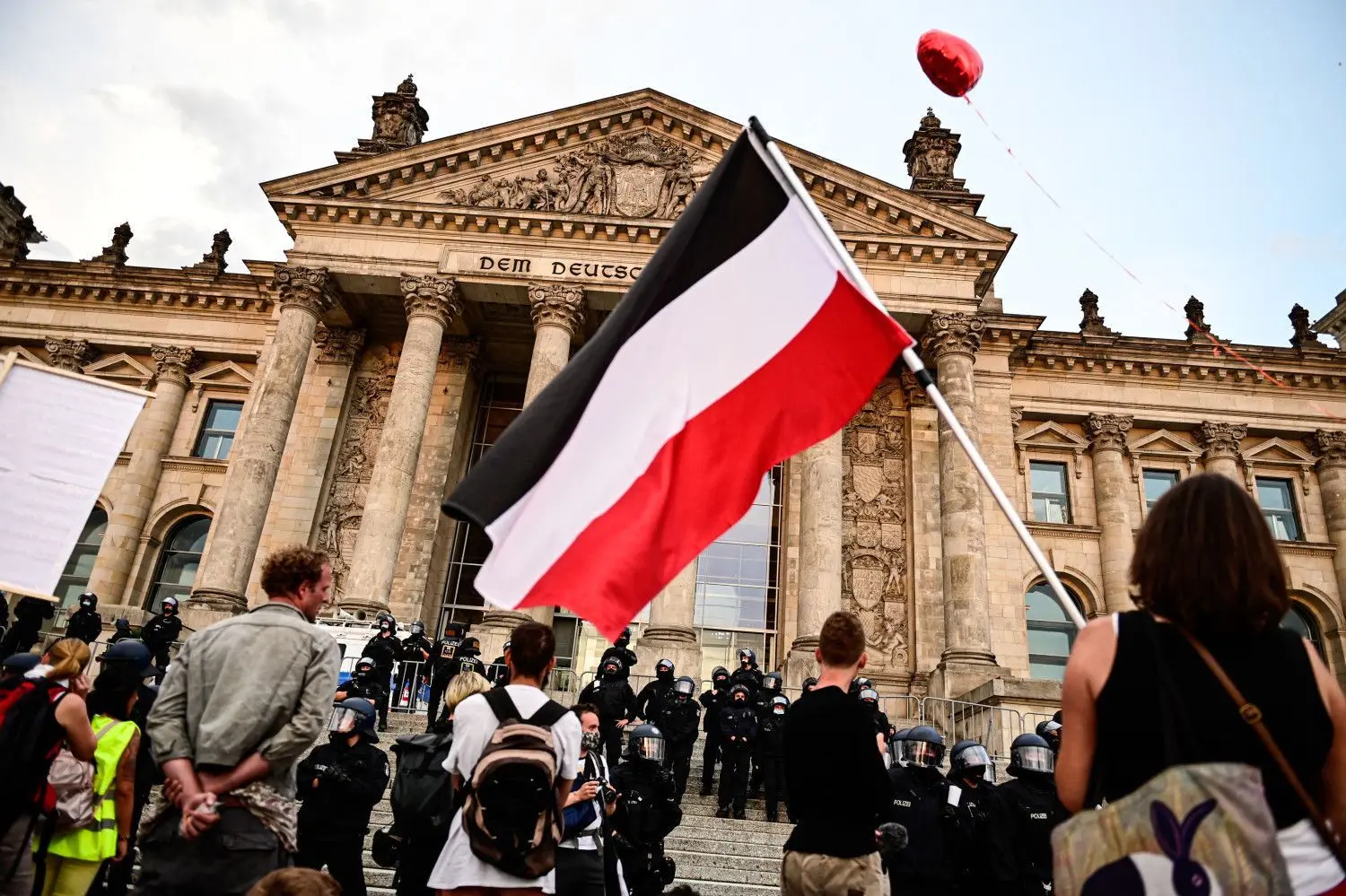 Teilnehmer einer Kundgebung gegen die Corona-Maßnahmen stehen vor dem Reichstag.