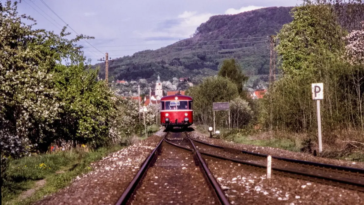 Blick vom Bahnhof in Boll auf einen Zug im Mai 1988. Hinter dem roten Schienenbus ist die Kirche von Dürnau zu sehen.⇥
Serie Boller Bahn 13 vom 04.05.88