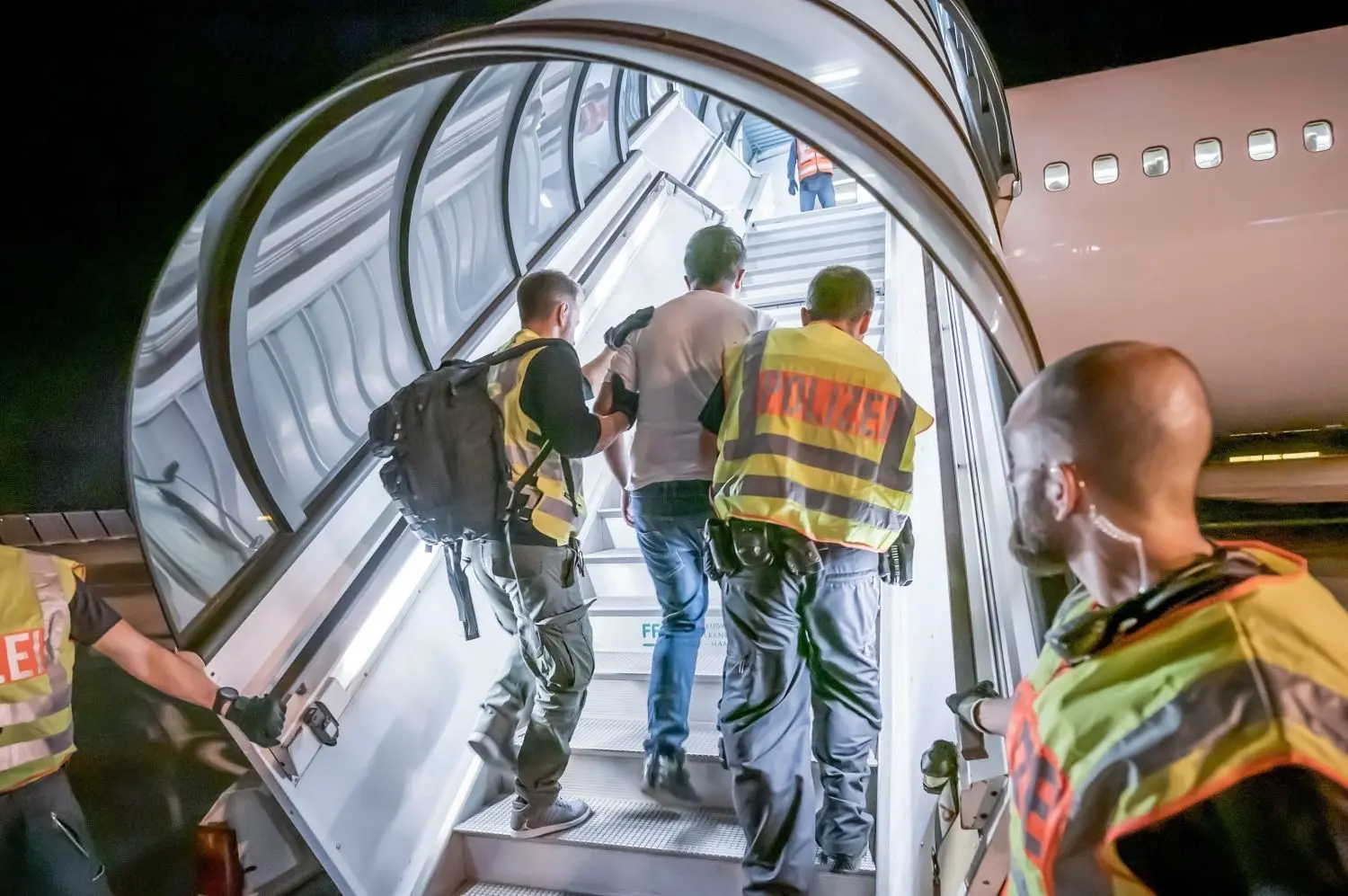 Polizeibeamte begleiten einen Afghanen auf dem Flughafen Leipzig-Halle in ein Charterflugzeug. ⇥