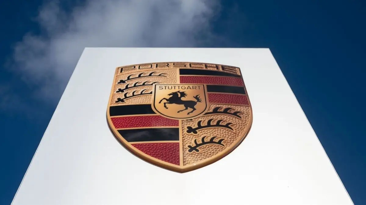 Das Logo der Porsche AG ist vor leicht bewölktem Himmel zu sehen. Nach dpa-Informationen prüft der Autobauer Porsche den Bau einer Batteriefabrik auf dem Areal des Flugplatzes Schwarzheide/Schipkau im Landkreis Oberspreewald-Lausitz. (zu dpa: «Neue Groß-Investition in Südbrandenburg möglich - Porsche im Gespräch») +++ dpa-Bildfunk +++