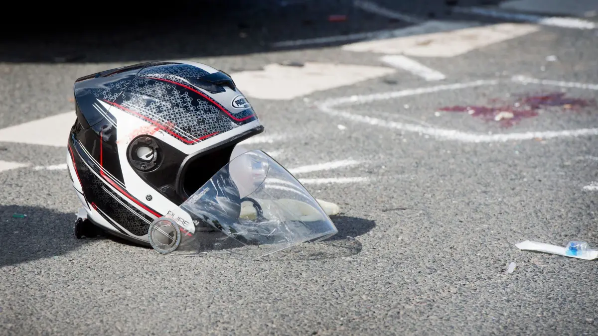 ARCHIV - 07.04.2016, Niedersachsen, Hannover: Ein beschädigter Motorradhelm liegt nach einem schweren Verkehrsunfall zwischen einem Motorrad und einem Auto auf einer Straße. Foto: Julian Stratenschulte/dpa +++ dpa-Bildfunk +++