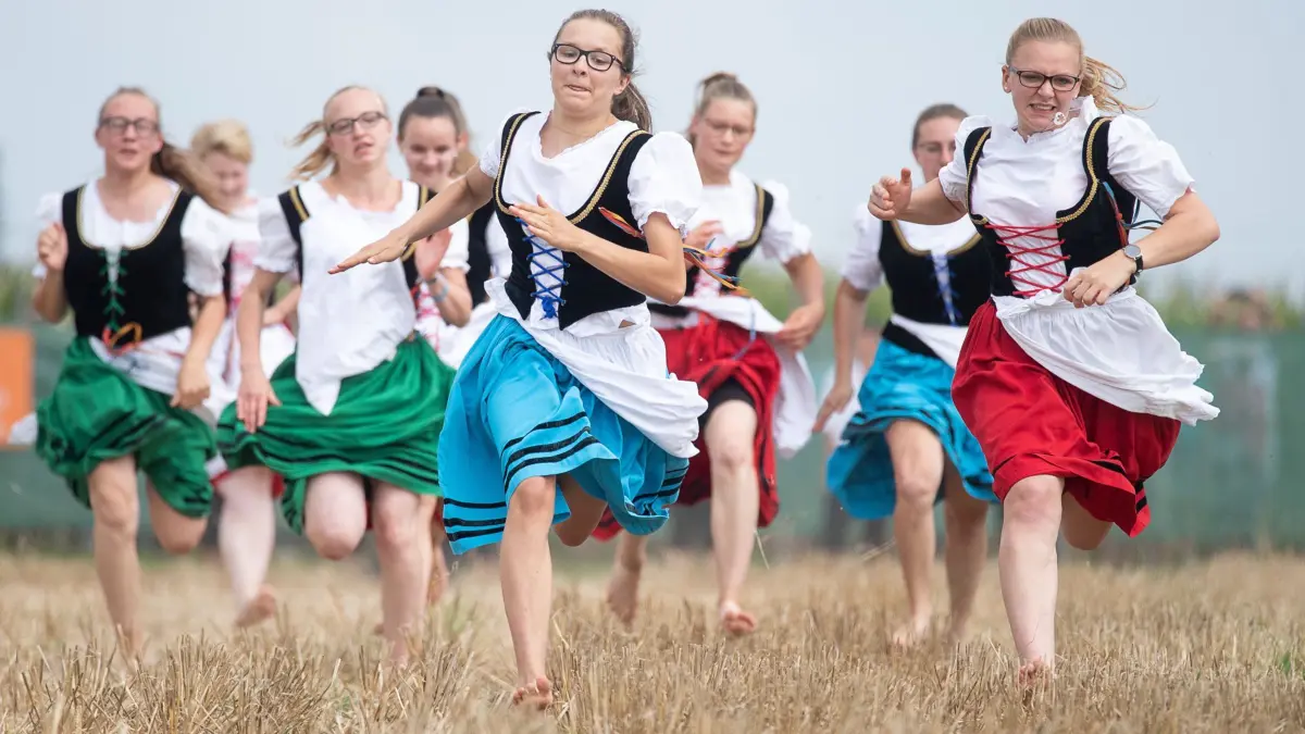 Schäfermädchen rennen während des Markgröninger Schäferlaufs über ein Stoppelfeld. Sophia Hagenlocher (M) hat den Schäferlauf gewonnen. (zu dpa: «Sommerserie: B wie Barfußrennen Schäferlauf») +++ dpa-Bildfunk +++
