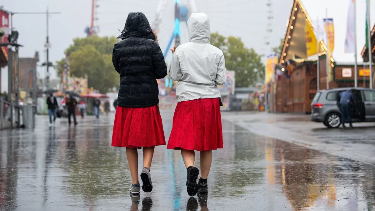 ARCHIV - 27.09.2019, Baden-Württemberg, Stuttgart: Zwei Bedienungen gehen zu Beginn des 174. Cannstatter Volksfests über den Platz. Der «Wasen» ist nach dem Münchner Oktoberfest das zweitgrößte Volksfest in Deutschland und dauert vom 27. September bis zum 13. Oktober. (zu dpa: «Nasser Einstieg in den Herbst - wenig Sonne im September») Foto: Sebastian Gollnow/dpa +++ dpa-Bildfunk +++