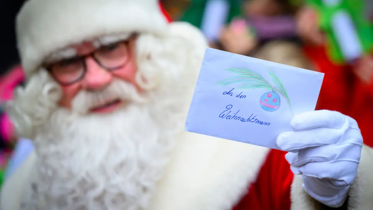 Der Weihnachtsmann steht vor dem Weihnachtspostamt und zeigt einen Brief mit einem Wunschzettel. Knapp sechs Wochen vor Heiligabend hat der Weihnachtsmann im brandenburgischen Himmelpfort wieder seine Wunschzettel-Filiale eröffnet. Im Jahr 1984, also vor 40 Jahren, schrieben die ersten beiden Kinder aus Sachsen und Berlin an den Weihnachtsmann nach Himmelpfort. Mittlerweile ist Himmelpfort die größte der bundesweit sieben Weihnachtspostfilialen, in der jährlich rund 300.000 Wunschzettel eintreffen. +++ dpa-Bildfunk +++