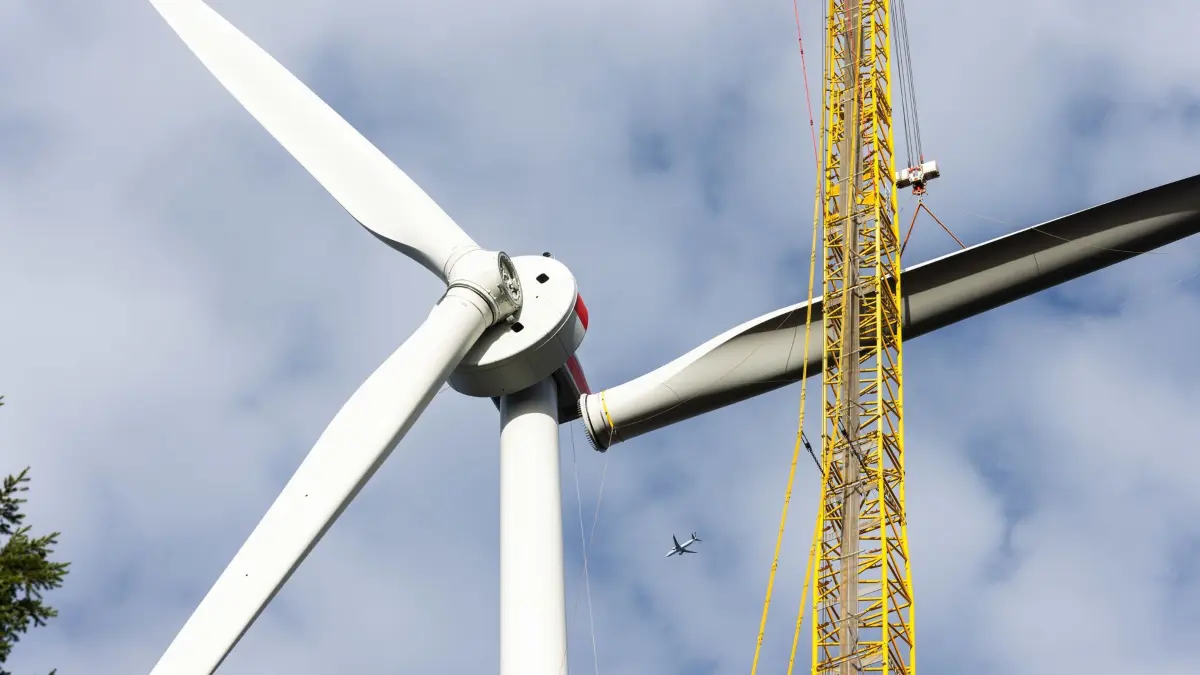 PRODUKTION - 17.10.2024, Baden-Württemberg, Freiburg: Ein Kran zieht das dritte Rotorblatt einer neuen Windkraftanlage auf der Holzschlägermatte am Schauinsland hoch. Die Anlage soll das dreifache der vorherigen Anlage liefern, die im Vorjahr nach 20 Betriebsjahren gesprengt wurde. (zu dpa: «Erneut nur wenige neue Windräder im Südwesten gebaut») Foto: Philipp von Ditfurth/dpa +++ dpa-Bildfunk +++