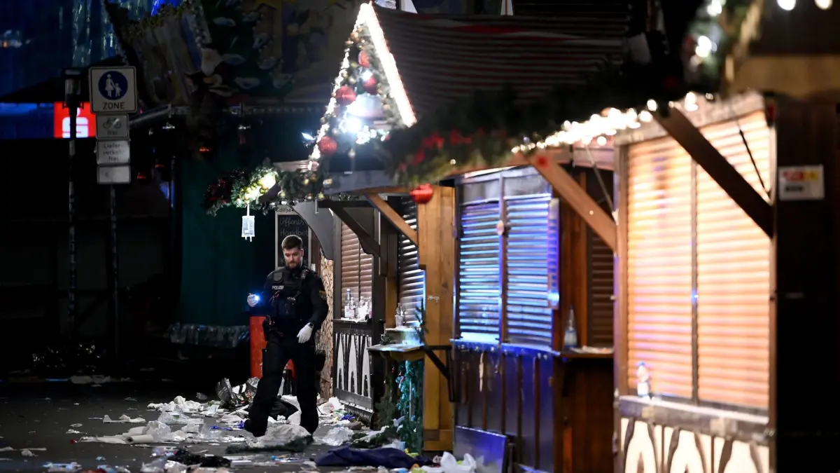 Auto fährt in Menschenmenge auf Magdeburger Weihnachtsmarkt: 20.12.2024, Sachsen-Anhalt, Magdeburg: Ein Polizist untersucht den Tatort auf dem Weihnachtsmarkt. Auf dem Weihnachtsmarkt in Magdeburg ist ein Autofahrer in eine Menschengruppe gefahren. Foto: Heiko Rebsch/dpa +++ dpa-Bildfunk +++