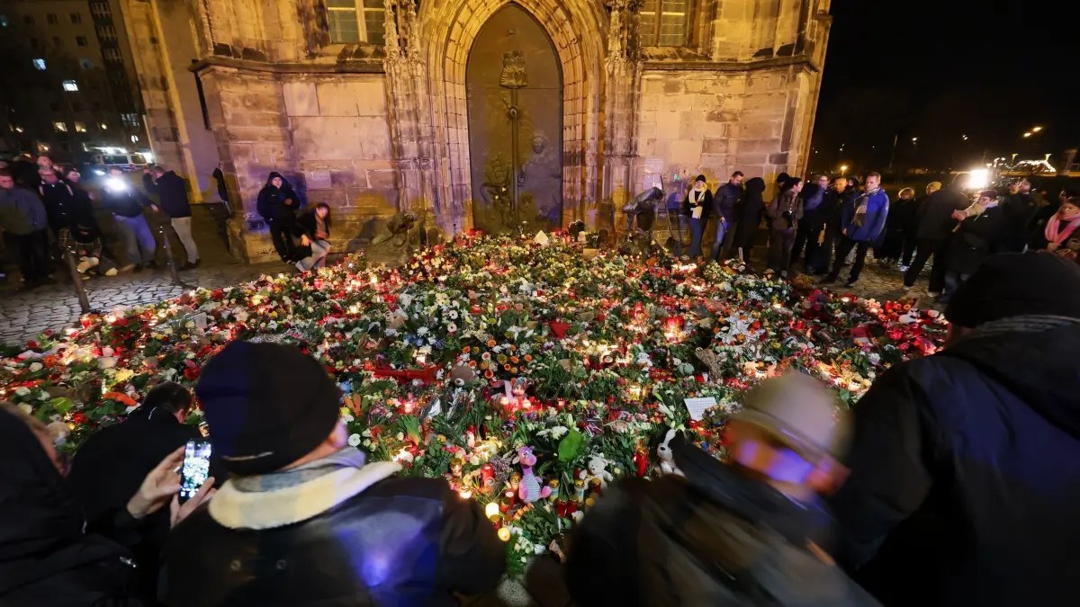 Nach Todesfahrt auf Weihnachtsmarkt in Magdeburg: 21.12.2024, Sachsen-Anhalt, Magdeburg: Mehrere Menschen legen Blumen und Kerzen am offiziellen Gedenkort an der Johanniskirche nieder. Am Vorabend war ein Autofahrer auf dem Magdeburger Weihnachtsmarkt in eine Menschengruppe gefahren. Es gab mehrere Tote und Verletzte. Foto: Jan Woitas/dpa +++ dpa-Bildfunk +++