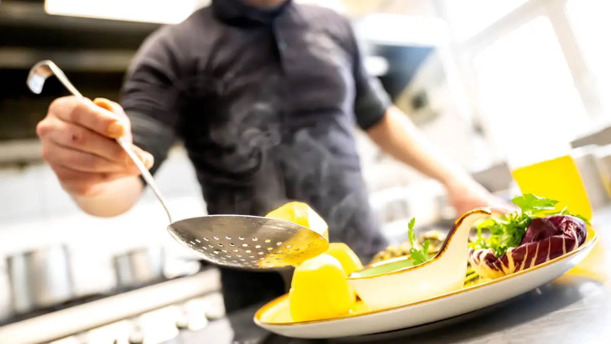 Essen wird in einem Restaurant auf einem Teller angerichtet. Der Hotel- und Gaststättenverband Dehoga in Niedersachsen sieht eine Chance, dass die Rückkehr zum normalen Mehrwertsteuersatz auf Restaurant-Essen doch noch abgewendet werden könnte. Die Bundesregierung hatte sich nach Angaben der Chefhaushälter von SPD, Grünen und FDP darauf verständigt, dass auf Speisen in der Gastronomie von Januar an wieder eine Umsatzsteuer von 19 Prozent statt 7 Prozent gilt. +++ dpa-Bildfunk +++