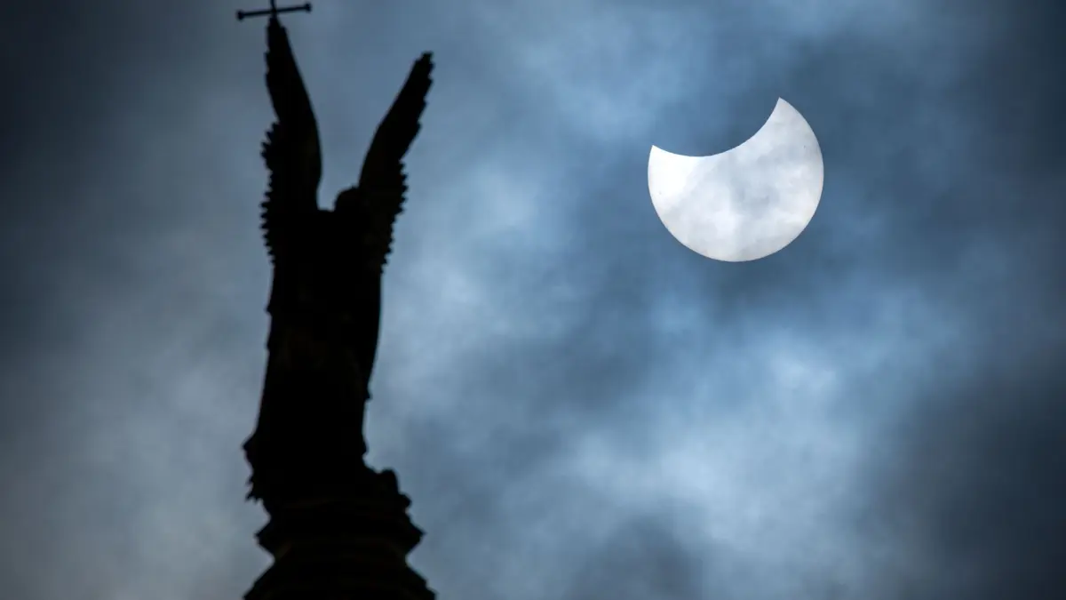 Partielle Sonnenfinsternis - Schwerin: ARCHIV - 25.10.2022, Mecklenburg-Vorpommern, Schwerin: Eine partielle Sonnenfinsternis ist über der vergoldete Statue des Erzengel Michael auf der Kuppel des Schweriner Schlosses zu sehen. (zu dpa: «Astronomische Jahresvorschau - Sonne, Mond und Sterne 2025») Foto: Jens Büttner/dpa +++ dpa-Bildfunk +++