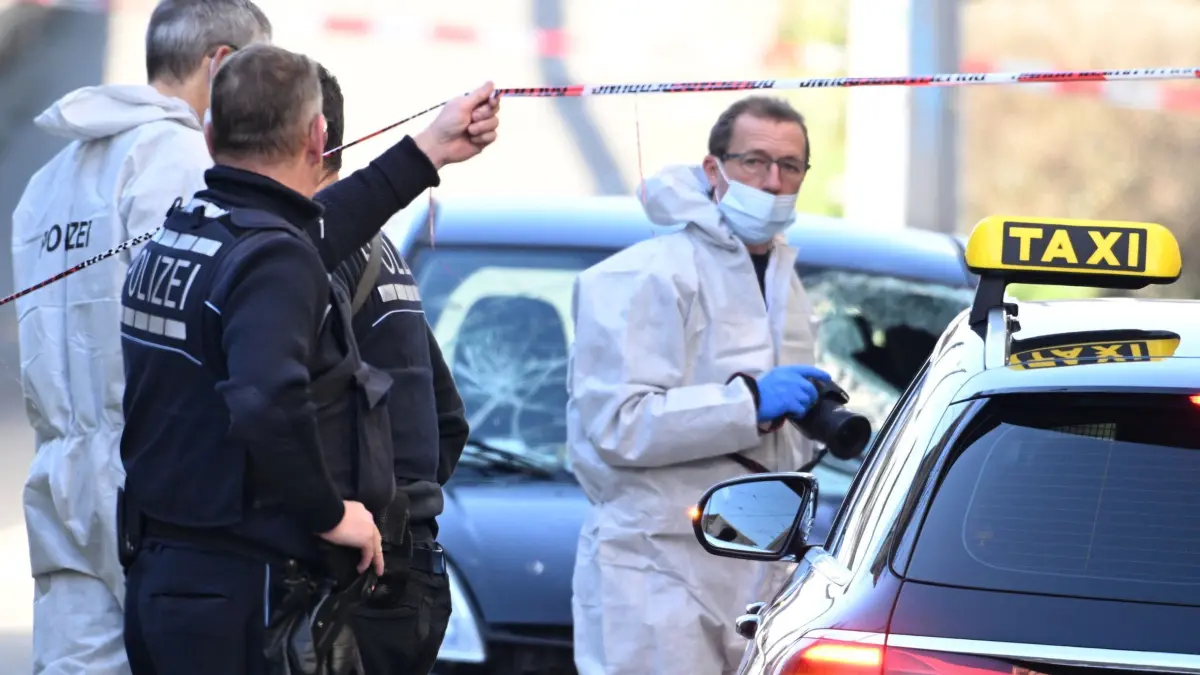 Polizeieinsatz in Mannheim: 03.03.2025, Baden-Württemberg, Mannheim: Beamte der Spurensicherung untersuchen ein beschädigtes Fahrzeug (hinten) an einer Zufahrt zur Rheinbrücke. Nach einem Vorfall mit einem Auto in der Mannheimer Innenstadt mit mindestens einem Toten und mehreren Verletzten ist der mutmaßliche Fahrer nach Polizeiangaben festgenommen worden. Nach Polizeiangaben war ein Fahrzeug in eine Menschenmenge gefahren. Foto: Boris Roessler/dpa +++ dpa-Bildfunk +++
