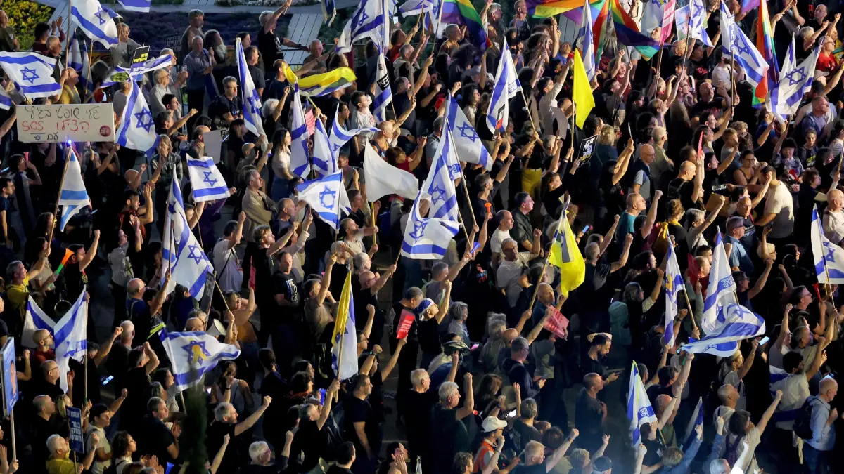Anti-government demonstrators raise flags as they protest against moves by the Israeli government to dismiss Attorney General Gali Baharav-Miara and the head of the internal security agency, Ronen Bar, at Habima Square in Tel Aviv, on March 27, 2025. Israel's parliament on March 27 passed a law expanding the power of politicians over judge appointments in defiance of a years-long protest movement against the judicial reforms pushed by Prime Minister Benjamin Netanyahu. (Photo by Jack GUEZ / AFP)