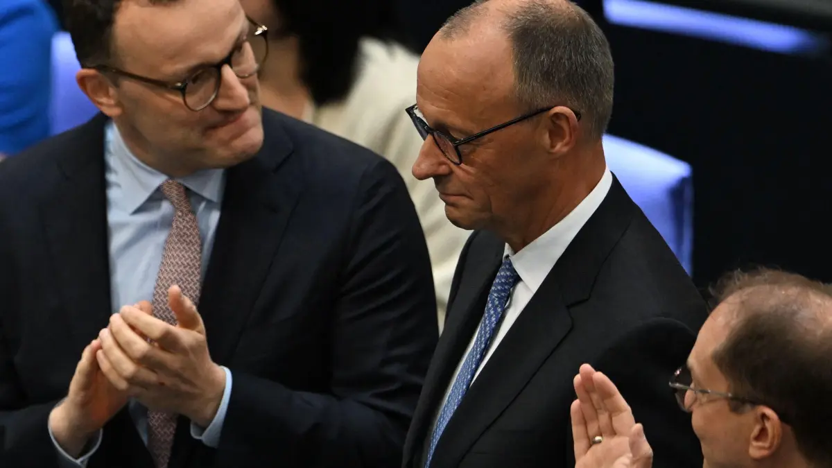Designated German Chancellor Friedrich Merz (C) is applauded by Parliamentary group leader of Germany's Christian Democratic Union (CDU) Jens Spahn (L) and designated German Interior Minister Alexander Dobrindt after the second round of voting during a session at the Bundestag (lower house of parliament), as MPs are to elect Germany's next Chancellor, in Berlin on May 6, 2025. German lawmakers voted for conservative leader Friedrich Merz to become chancellor Tuesday in a second-round vote after he suffered a shock defeat in the initial ballot. (Photo by RALF HIRSCHBERGER / AFP)