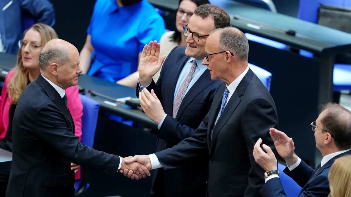 Bundestag - Kanzlerwahl: 06.05.2025, Berlin: Der designierte Bundeskanzler Friedrich Merz (CDU, 2.v.r.) und der geschäftsführende Bundeskanzler Olaf Scholz (SPD, l) schütteln sich neben Jens Spahn (CDU, 2.v.l.), Vorsitzender der CDU/CSU Bundestagsfraktion, die Hände im Bundestag beim zweiten Durchgang der Kanzlerwahl. Daneben applaudiert Alexander Dobrindt (CSU, 2.v.l.), designierter Bundesinnenminister. Merz ist im zweiten Anlauf im Bundestag zum zehnten Kanzler der Bundesrepublik Deutschland gewählt worden. Foto: Kay Nietfeld/dpa +++ dpa-Bildfunk +++