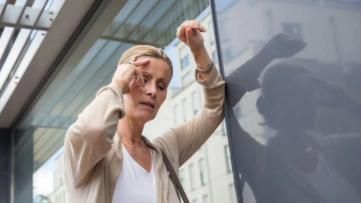 Frau mit Schwindelanfall stützt sich an einer Hauswand ab: ILLUSTRATION - Bei Frauen kann sich ein Schlaganfall mit diffusen Symptomen wie Schwindel oder Verwirrtheit bemerkbar machen. (zu dpa: «Schlaganfall: Frauen haben oft andere Symptome») Foto: Christin Klose/dpa-mag - Honorarfrei nur für Bezieher des Dienstes dpa-Magazin +++ dpa-Magazin +++