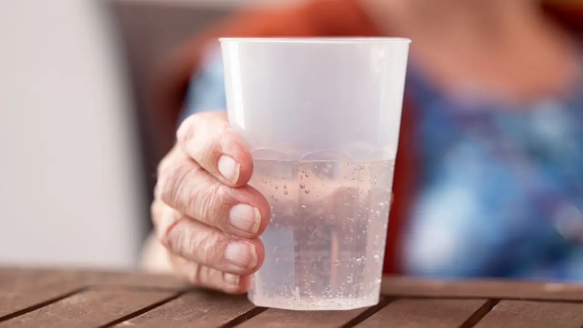 Hitze in Deutschland: 02.07.2025, Sachsen, Dresden: Die Bewohnerin eines Seniorenzentrums hält einen Becher mit Wasser. Foto: Sebastian Kahnert/dpa +++ dpa-Bildfunk +++