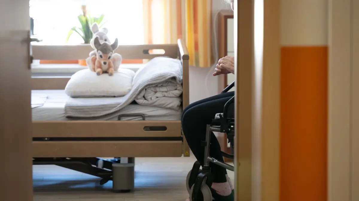 Pflegeheim: ARCHIV - 03.04.2025, Sachsen, Dresden: Ein Bewohner sitzt in einem Altenheim in seinem Zimmer in einem Rollstuhl. Auf dem gemachten Bett liegt ein Stofftier. (zu dpa: «Pflege im Heim noch teurer - Druck für Entlastung») Foto: Sebastian Kahnert/dpa +++ dpa-Bildfunk +++