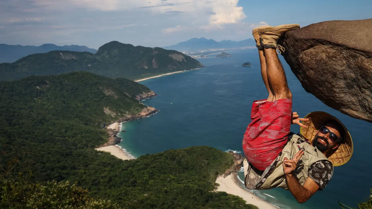 Ein Mann hängt für ein Bild an dem Felsen Pedra do Telegrafo in Rio. Touristen und Einheimische lassen sich hier an der Spitze des Felsens in scheinbar waghalsigen Posen ablichten.