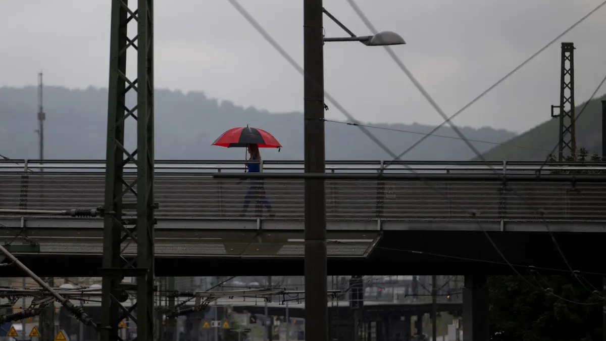 Regen iin Baden-Württemberg: 10.09.2025, Baden-Württemberg, Eßlingen: Eine Person geht mit einem Regenschirm über einen Steg. Foto: Marijan Murat/dpa +++ dpa-Bildfunk +++