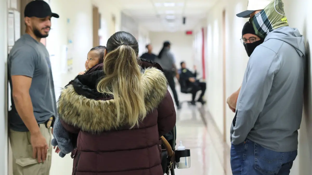 ICE Detains Immigrants Inside New York City Courthouses: NEW YORK, NEW YORK - OCTOBER 14: A woman holds a baby as she walks past federal agents patrolling the halls of immigration court at the Jacob K. Javitz Federal Building on October 14, 2025 in New York City. Immigration and Customs Enforcement (ICE) agents and other federal agencies continue to make detainments in immigration courts as people attend their court hearings despite a government shutdown thats going on it's thirteenth day. Michael M. Santiago/Getty Images/AFP (Photo by Michael M. Santiago / GETTY IMAGES NORTH AMERICA / Getty Images via AFP)