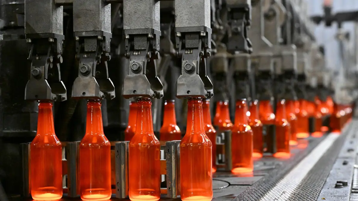 Behälterglashersteller Wiegand-Glas: ARCHIV - 07.02.2024, Thüringen, Schleusingen: Glühend heiße Glasflaschen kommen aus einer Anlage beim Behälterglashersteller Wiegand-Glas in Schleusingen. (zu dpa: «Glasindustrie hat Energieverbrauch deutlich gesenkt») Foto: Martin Schutt/dpa +++ dpa-Bildfunk +++