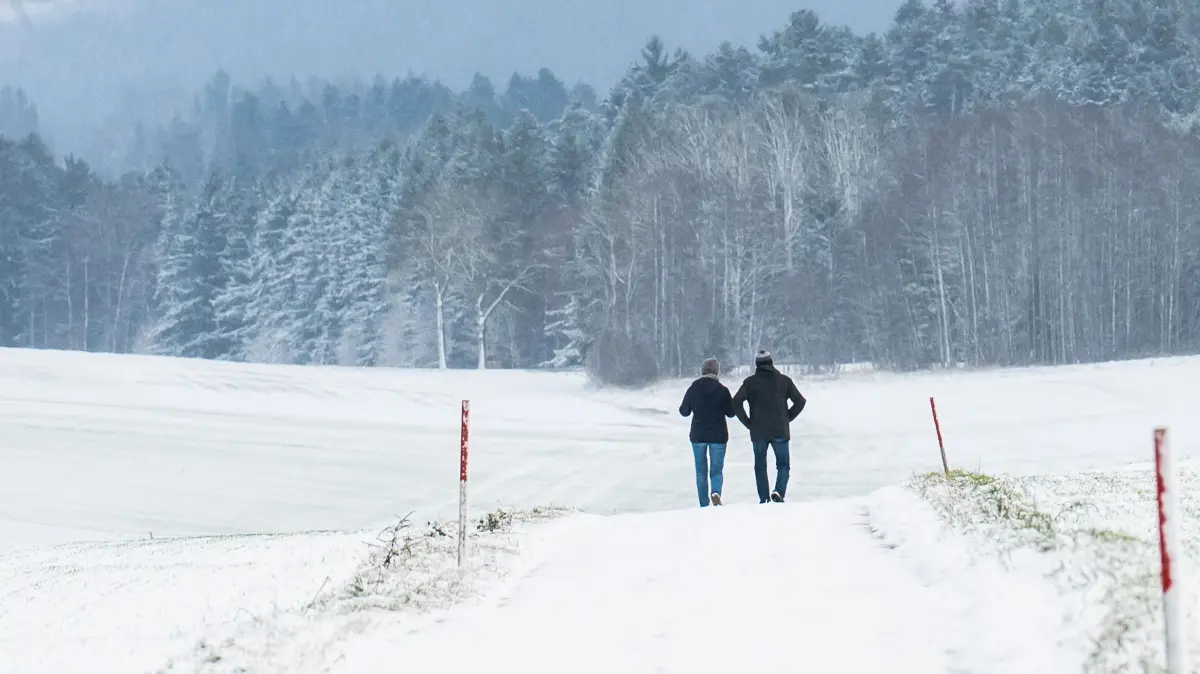 Eine Frau und ein Mann gehen auf einem zugeschneiten Weg bei Bösingen (Landkreis Rottweil) spazieren. Im Schwarzwald werden bis zu 20 Zentimeter Neuschnee erwartet. +++ dpa-Bildfunk +++