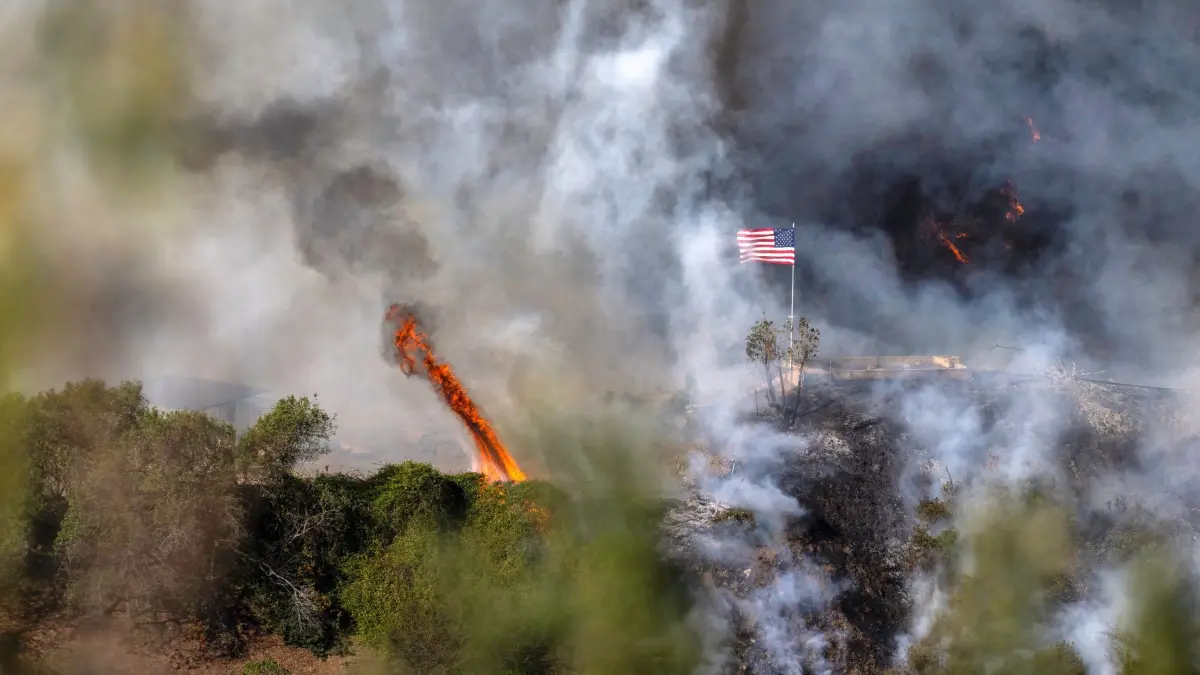 Jahreswechsel 2025: 11.01.2025, USA, Los Angeles: Eine amerikanische Flagge weht über einem Teil des Mandeville Canyon, der durch das Palisades-Feuer zerstört wurde. Foto: Mark Edward Harris/ZUMA Press Wire/dpa +++ dpa-Bildfunk +++