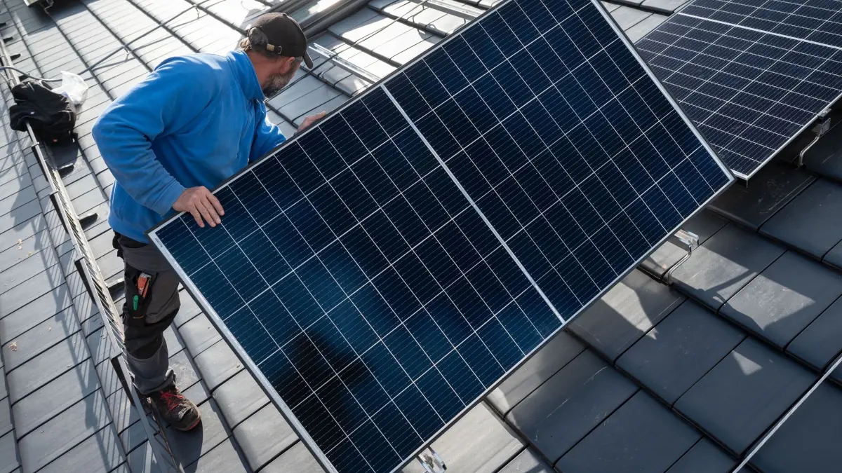 Montage von Photovoltaik-Modulen: ARCHIV - 13.10.2021, Baden-Württemberg, Stuttgart: Mitarbeiter einer Solar-Firma montieren Photovoltaikmodule auf dem Dach eines Wohnhauses. (zu dpa: «Eon-Chef Birnbaum: «Mieter eher Verlierer der Energiewende»») Foto: Marijan Murat/dpa +++ dpa-Bildfunk +++