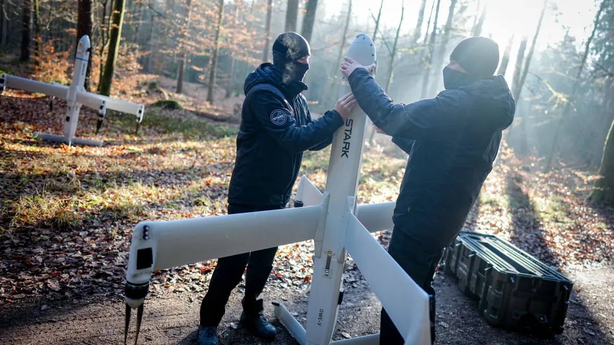 Deutsche Drohnenwaffe ist komplett: Gefechtskopf getestet: ARCHIV - 18.12.2025, Bayern, Schrobenhausen: Mitarbeiter der Firma Stark Defence, die nicht erkannt werden möchten, demonstrieren in einem Waldstück in der Nähe des Sprengplatzes den Aufbau ihrer Drohnenwaffe «Virtus». Eine Kamikaze-Drohne, die auch Loitering Munition (lauernde Munition) genannt wird, dieses Typs wurde später mit einem Gefechtskopf des Herstellers TDW erfolgreich auf dem Sprengplatz des Rüstungsunternehmens MBDA in Bayern getestet. Die Hersteller Stark und TDW haben den ersten scharfen Schuss einer deutschen Loitering Munition demonstriert und die Wirkung auf Panzerstahl untersucht. (zu dpa: «Kamikazedrohnen für die Bundeswehr: Ausschuss entscheidet») Foto: Kay Nietfeld/dpa +++ dpa-Bildfunk +++