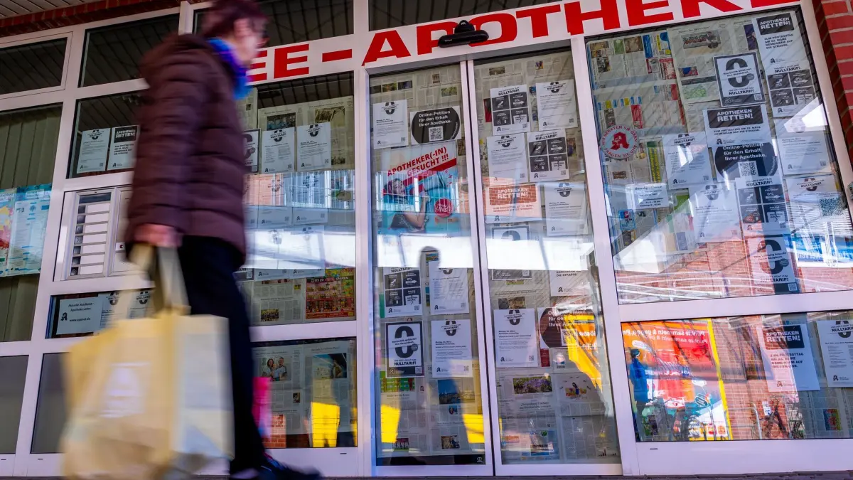 Bundesweiter Protesttag von Apotheken: 23.03.2026, Mecklenburg-Vorpommern, Grevesmühlen: Eine Frau geht am bundesweiten Apotheken-Protesttag an der zugeklebten Eingangstür zur See-Apotheke vorbei. Apotheken sind am Protesttag von Apotheken für höhere Vergütungen aufgerufen ihre Geschäfte geschlossen zu halten. Foto: Jens Büttner/dpa +++ dpa-Bildfunk +++