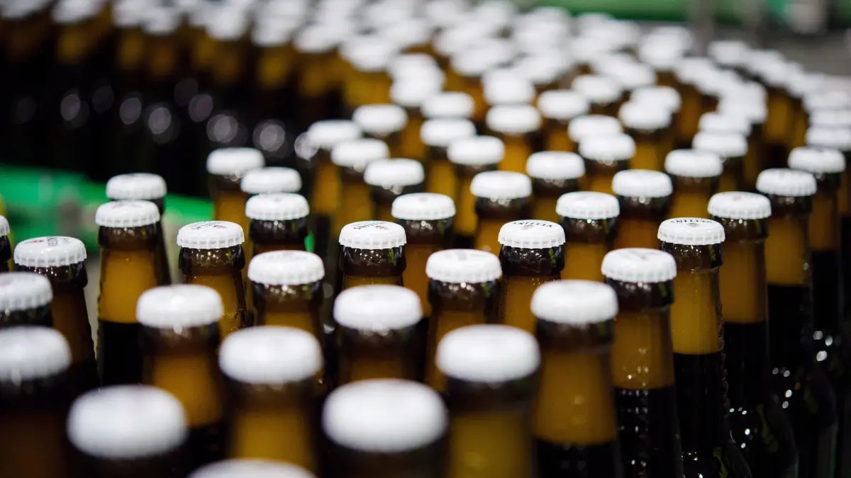 Bierproduktion: ARCHIV - 04.01.2018, Nordrhein-Westfalen, Meschede-Grevenstein: Bierflaschen mit Kronkorken laufen in der Produktion der Veltins-Brauerei in Meschede-Grevenstein über die Förderbänder einer Befüllungsanlage. (zu dpa: «Bierhersteller erwarten schwieriges Jahr») Foto: Rainer Jensen/dpa +++ dpa-Bildfunk +++