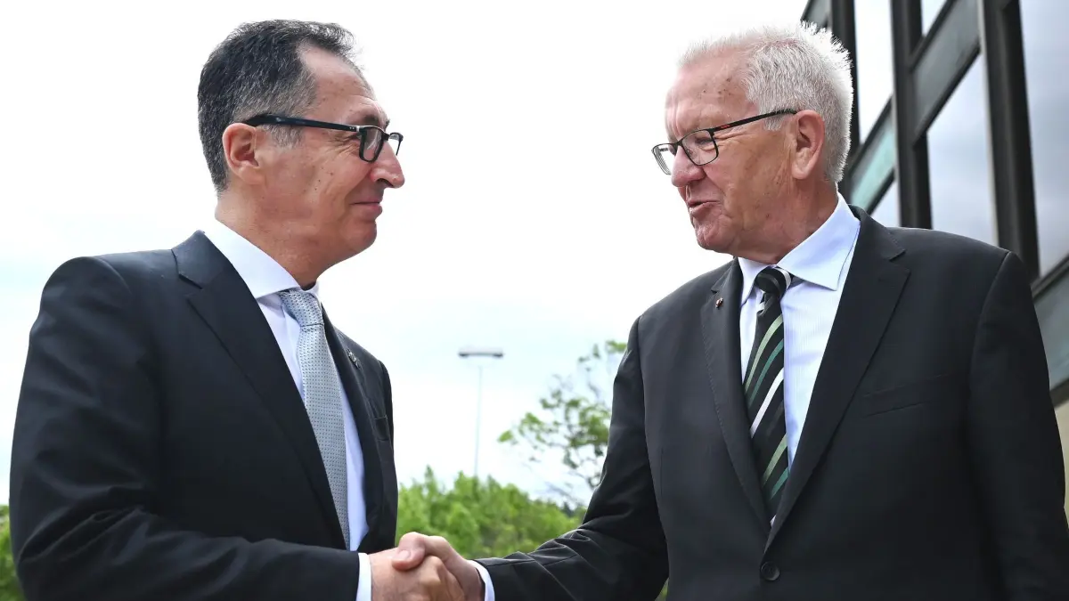 Özdemir wird Ministerpräsident von Baden-Württemberg: 13.05.2026, Baden-Württemberg, Stuttgart: Winfried Kretschmann (Bündnis 90/Die Grünen,r), scheidender Ministerpräsident von Baden-Württemberg, und Cem Özdemir (Bündnis 90/Die Grünen), designierter Ministerpräsident von Baden-Württemberg, reichen sich vor dem Haus des Landtags die Hände. Özdemir (Bündnis 90/Die Grünen) soll im Landtag zum neuen Ministerpräsidenten von Baden-Württemberg gewählt werden. - recrop Foto: Marijan Murat/dpa +++ dpa-Bildfunk +++