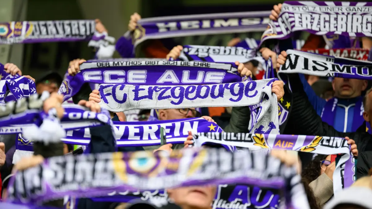 Aue ist finanziell für einen Wiederaufstieg gerüstet: ARCHIV - 08.05.2026, Sachsen, Aue: Fußball, Männer: 3. Liga, FC Erzgebirge Aue - MSV Duisburg, 37. Spieltag, Erzgebirgsstadion, Aues Fans halten Fanschals hoch. Aue ist wirtschaftlich für einen Wiederaufstieg gewappnet. (zu dpa: «Aue-Vorstand sieht «realistische Chance» für Wiederaufstieg») Foto: Robert Michael/dpa +++ dpa-Bildfunk +++