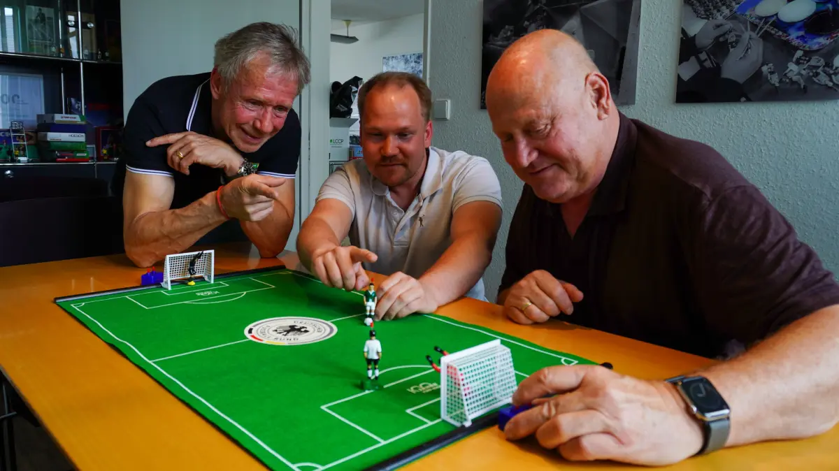 Jochen, Leonard und Mathias Mieg messen sich in einer Partie Tipp-Kick.