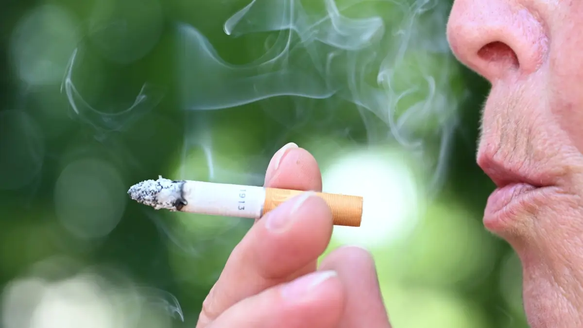 Raucheranteil in der Bevölkerung: PRODUKTION - 27.05.2026, Baden-Württemberg, Stuttgart: Eine Raucherin hält eine brennende Zigarette in der Hand und bläst Rauch aus. (zu dpa: «Statistik: Etwa ein Viertel der Thüringer raucht») Foto: Bernd Weißbrod/dpa +++ dpa-Bildfunk +++