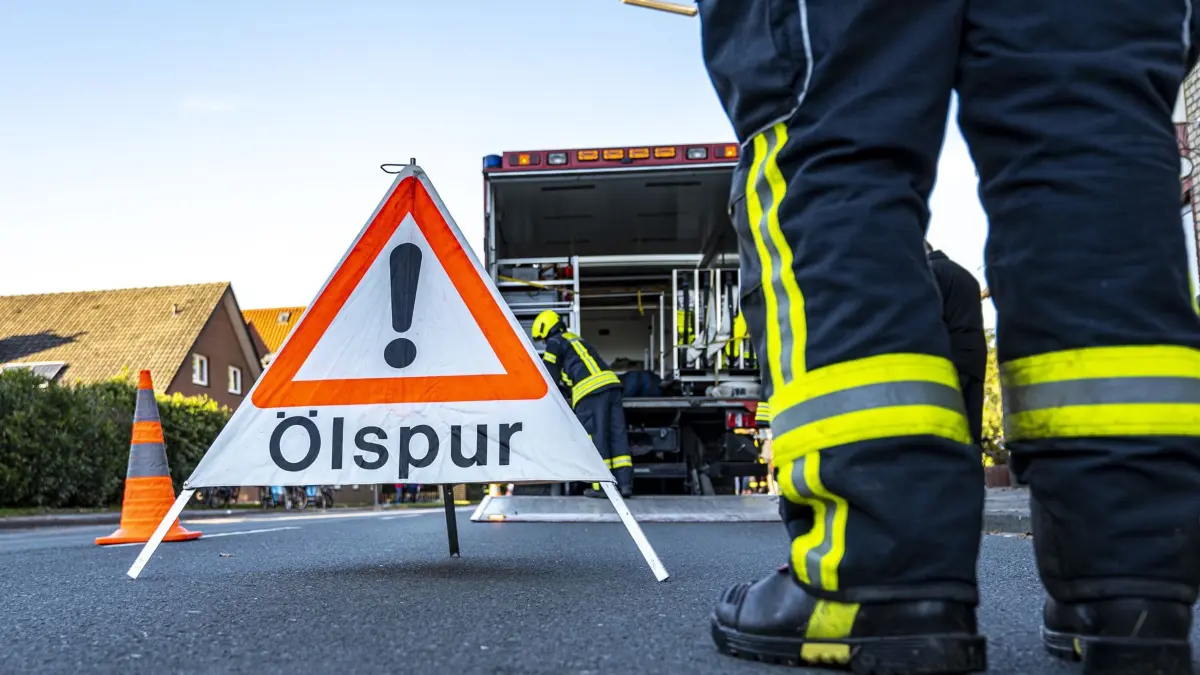 PRODUKTION - 09.10.2021, Nordrhein-Westfalen, Wadersloh: Ein Feuerwehrmann steht neben einem Warnschild mit der Aufschrift «Ölspur». (zu dpa: «Rettungswagen stößt mit Tanklaster zusammen») Foto: David Inderlied/dpa +++ dpa-Bildfunk +++
