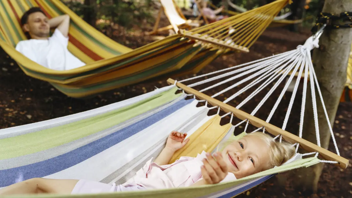 Smiling girl relaxing in hammock with man outdoors in forest: Smiling girl relaxing in hammock with man outdoors in forest model released, Symbolfoto, NSTF00556