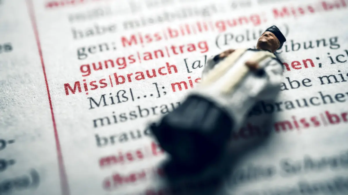 Miniaturfigur eines Priesters in einem Wörterbuch mit dem Wort Missbrauch, Symbolfoto Missbrauchsskandal *** Miniature figure of a priest in a dictionary with the word abuse symbol photo abuse scandal