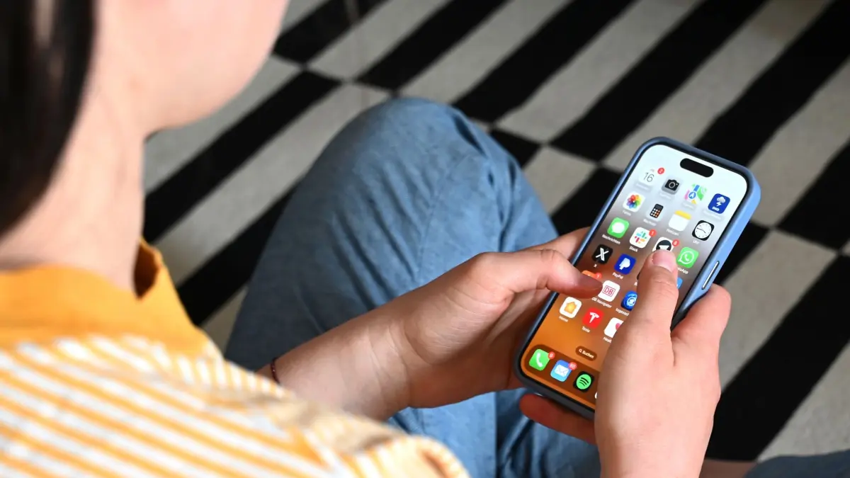 Soziale Medien: SYMBOLBILD - 17.05.2025, Sachsen, Leipzig: Eine Jugendliche sitzt auf dem Boden und nutzt ein Smartphone - auf dem Display sind verschiedene Apps zu sehen. (zu dpa: «TikTok und Co.: Kommt ein Social-Media-Verbot für Kinder?») Foto: Elisa Schu/dpa +++ dpa-Bildfunk +++