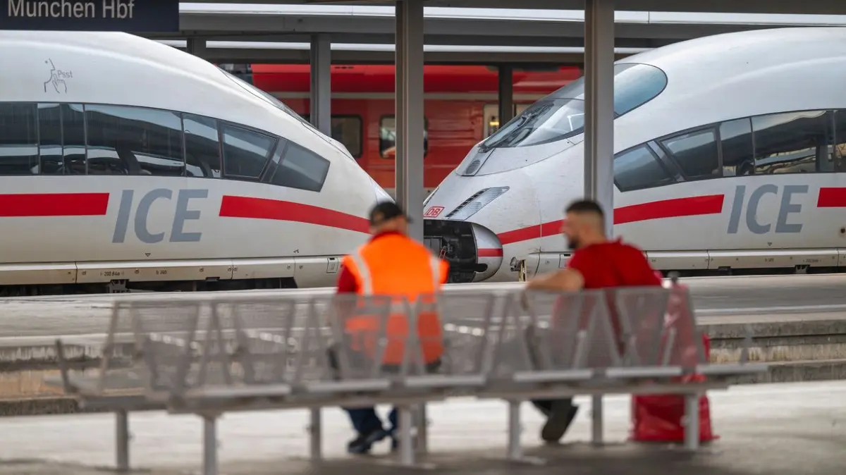 Zwei Männer sitzen am Morgen, nach dem bundesweiten Ausfall bei der Deutschen Bahn, am Hauptbahnhof München vor einem ICE-Zug. Die Störung bei der Deutschen Bahn ist nach Unternehmensangaben behoben. Der Zugverkehr läuft wieder an, es wird aber zu Folgeverspätungen und kurzfristigen Fahrtausfällen kommen.