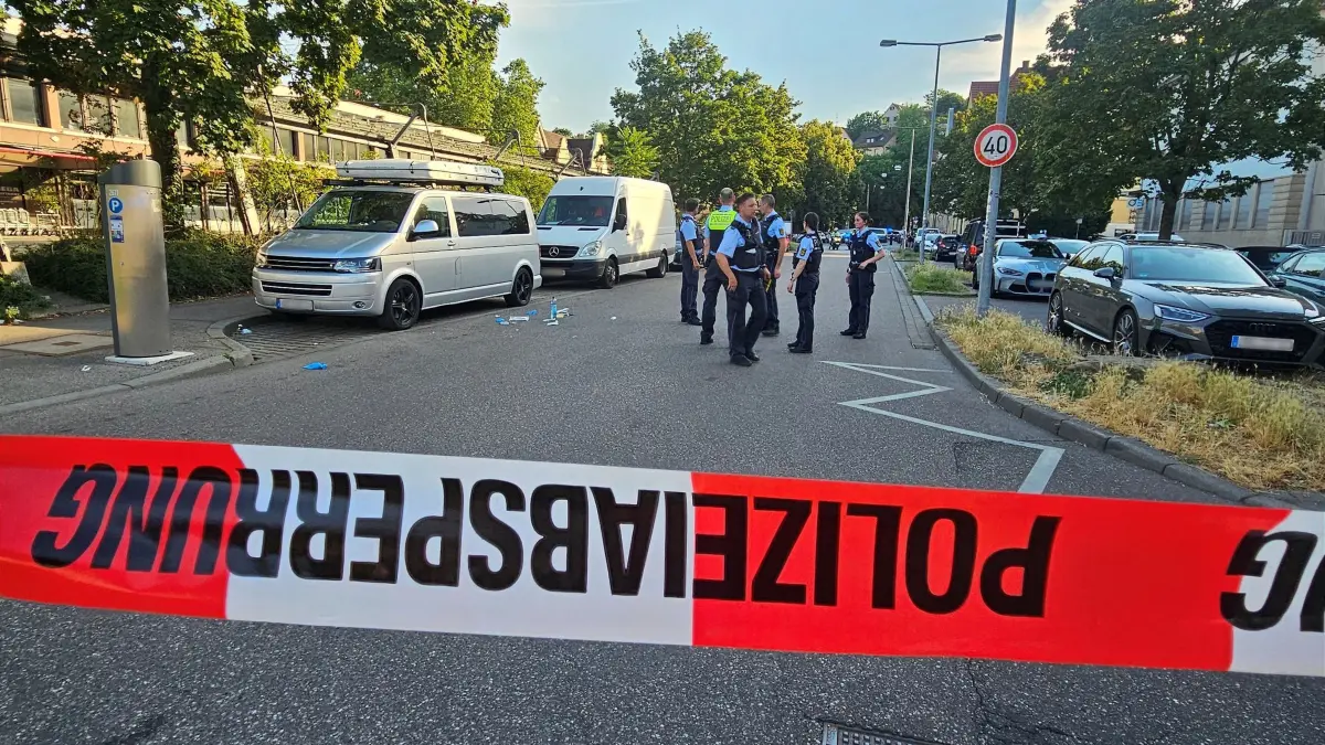 Größerer Polizeieinsatz in Stuttgart: 26.06.2026, Baden-Württemberg, Stuttgart: Einsatzkräfte der Polizei stehen am Tatort hinter einem Absperrband im Stuttgarter Osten. Die Polizei ist wegen eines Körperverletzungsdelikts zu einem größeren Einsatz ausgerückt, wie eine Polizeisprecherin mitteilte. Nach dem oder den Tätern werde gefahndet. Foto: Andreas Rosar/dpa +++ dpa-Bildfunk +++