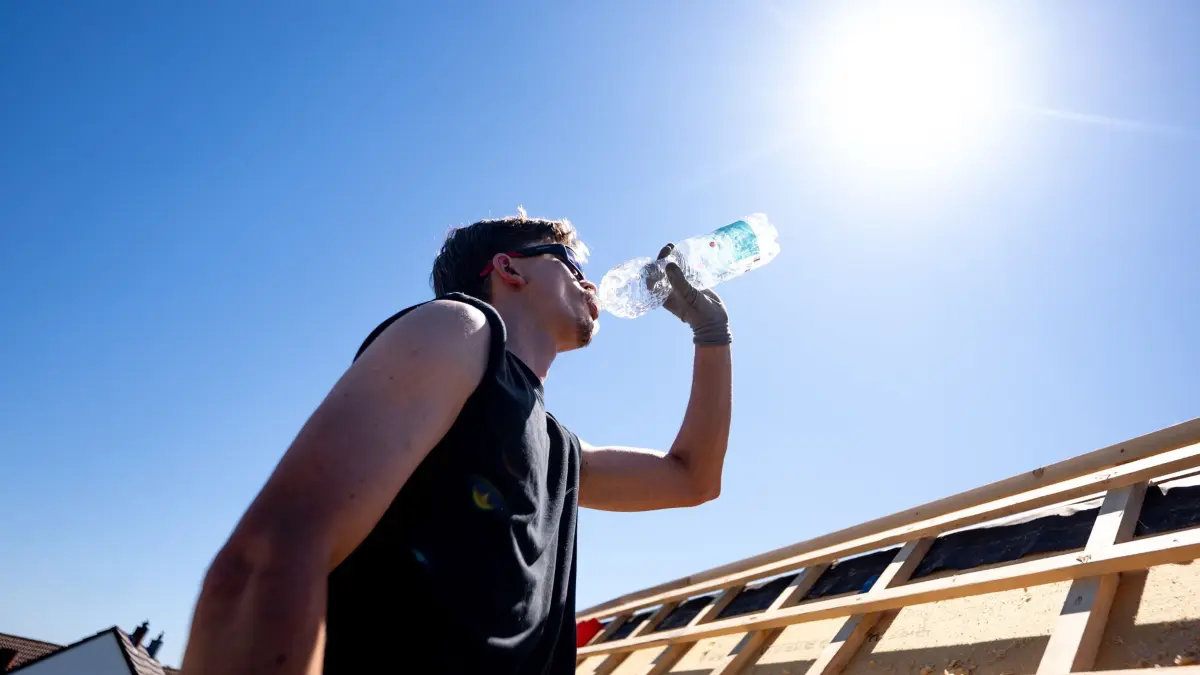 Wetter in Nordrhein-Westfalen: ARCHIV - 26.05.2026, Nordrhein-Westfalen, Sankt Augustin: Ein Dachdecker der Firma «Dachdecker Ditscheid» trinkt Wasser unter der sengenden Sonne bei über 30 Grad auf dem Dach eines Hauses im Rhein-Sieg-Kreis.
Alle 20 Minuten sollte man etwas trinken, wenn man sich in der Hitze viel bewegt. (zu dpa: «Deutschland glüht: 41,5 Grad und Hitzerekorde gebrochen») Foto: Benjamin Westhoff/dpa +++ dpa-Bildfunk +++