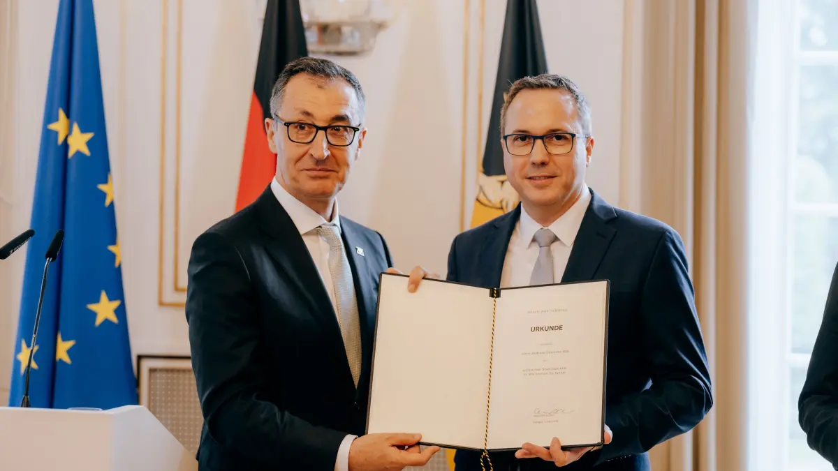 Cem Özdemir übergibt die Ernennungsurkunde an Kultusstaatssekretär Andreas Deuschle (CDU, rechts).