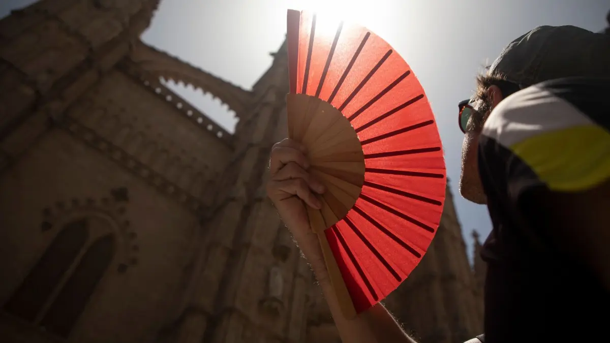 Hitze in Spanien: ARCHIV - 22.06.2026, Spanien, Palma: Eine Frau kühlt sich mit einem Fächer ab. Die Insel Mallorca erlebt derzeit sehr hohe Temperaturen. (zu dpa: «Spaniens Wetterdienst warnt vor neuer Hitzewelle») Foto: Clara Margais/dpa +++ dpa-Bildfunk +++