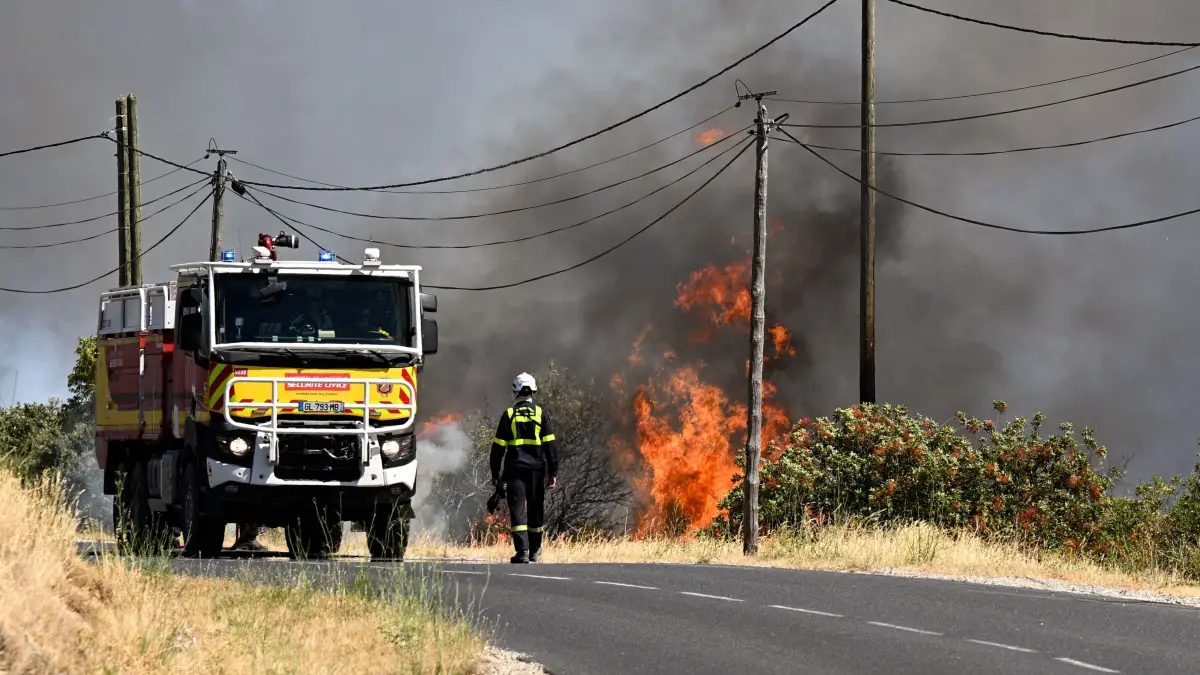Ein Feuerwehrmann der französischen Zivilschutzbehörde geht auf einer Straße neben einem Waldbrand in der Nähe von Ille-sur-Têt. Ein Waldbrand war am 4. Juli in einem schwer zugänglichen Gebirgsmassiv in der Nähe von Trevillach ausgebrochen.
