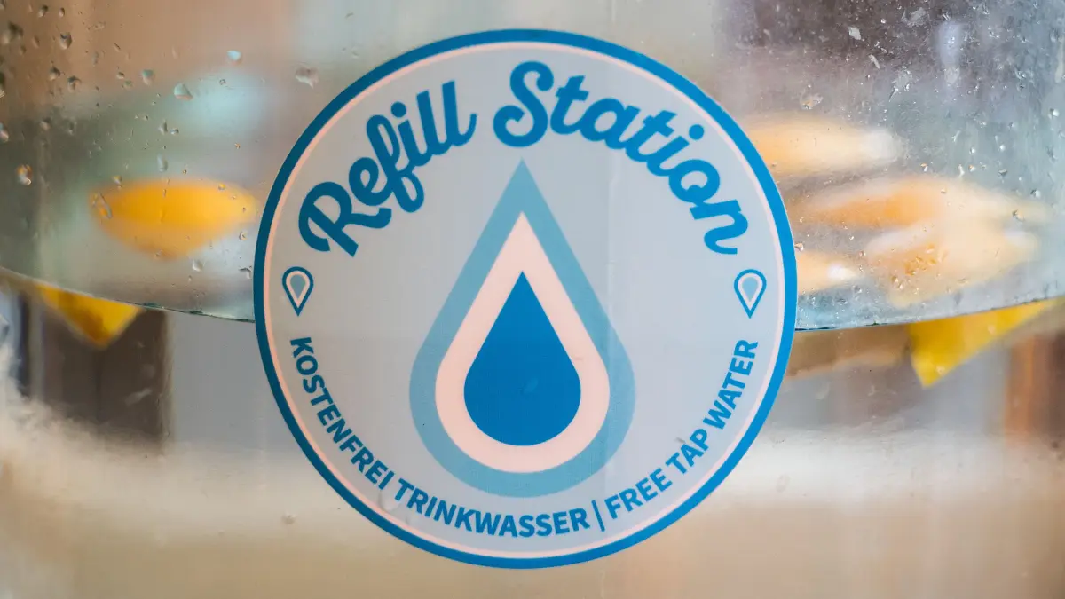 09.08.2018, Hessen, Frankfurt am Main: Der Aufkleber "Refill-Station" weisst auf die kostenlose Abgabe von Trinkwasser hin. Die Non-Profit-Organisation "Refill Deutschland" wurde 2017 gegründet und setzt sich für die Vermeidung von Plastikmüll ein. In sogenannten Refill-Stationen (Geschäfte, Restaurants, Büros) kann kostenlos Leitungswasser in mitgebrachte Trinkflaschen abgefüllt werden. Auch in Frankfurt gibt es inzwischen mehrere Anlaufstellen. Foto: Andreas Arnold/dpa +++ dpa-Bildfunk +++