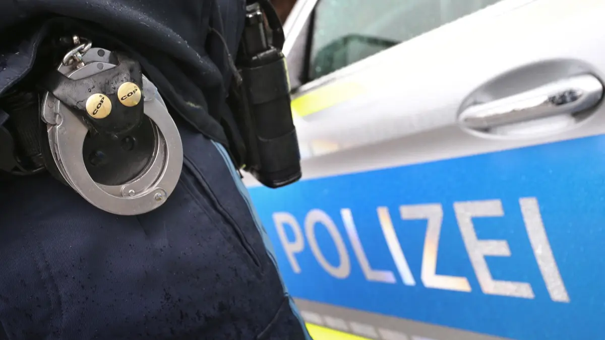 Polizei: ARCHIV - 15.03.2019, Bayern, Kempten: ILLUSTRATION - Ein Polizist mit Handschellen und einer Pistole am Gürtel steht vor einem Streifenwagen. (zu dpa: «Streit mit Jugendlichen - Mann zückt Schreckschusspistole») Foto: Karl-Josef Hildenbrand/dpa +++ dpa-Bildfunk +++